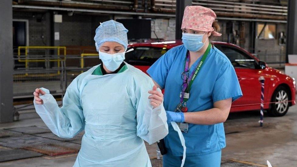 Medical staff put on their personal protective equipment (PPE) at an MOT testing centre in Belfast, Northern Ireland