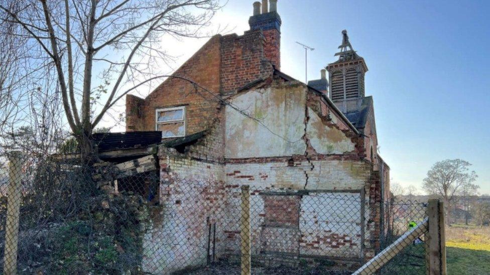 Side view of two-storey brick building, showing crumbling exterior wall