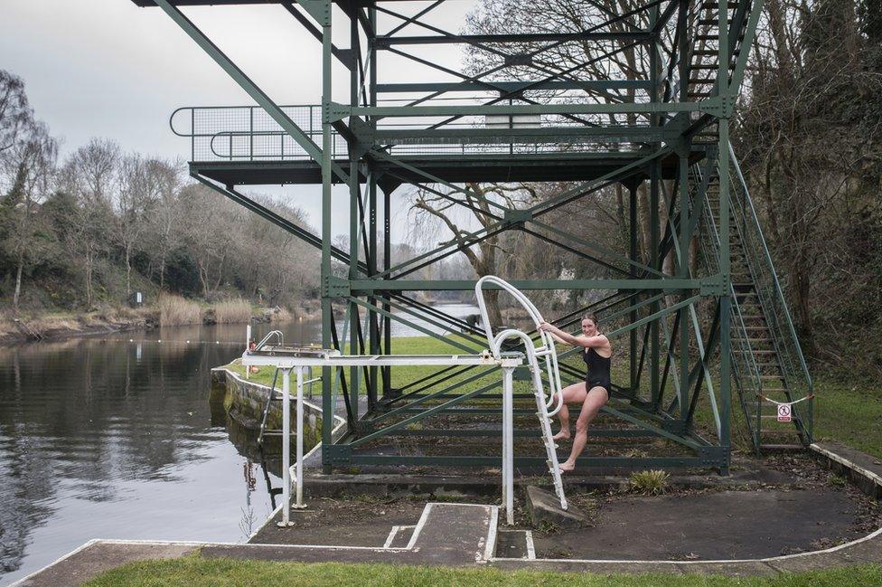 A woman climbs the diving board