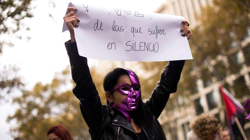 A woman holds a placard reading "We are the voice of those who suffer in silence" during a demonstration under the slogan "Together we buried the patriarchal order" to mark the International Day for the Elimination of Violence against Women in Barcelona