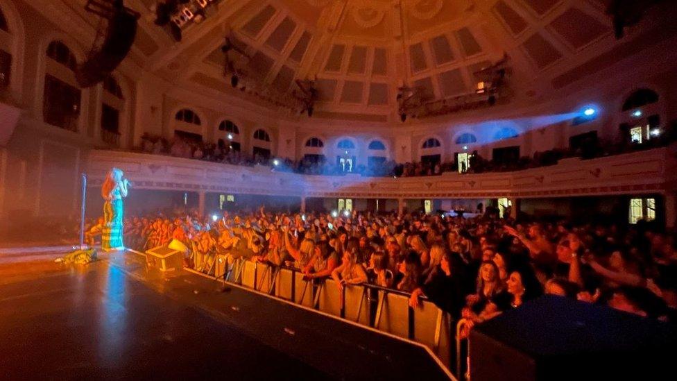 A performer on stage in front of a crowd at the Villa Marina's Royal Hall