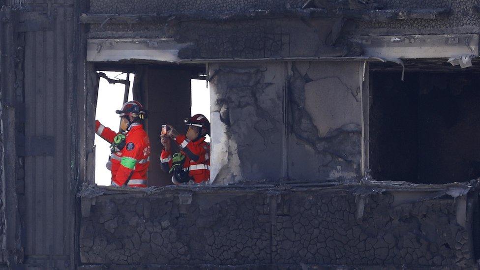 firemen search burnt out shell of Grenfell Tower