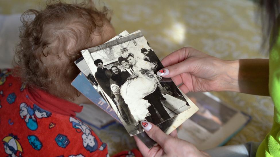 Hanna Kostseva looks at a photograph of her parents' wedding