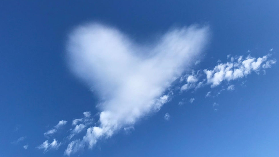 Clear blue skies with a love heart shaped cloud in the centre of the image