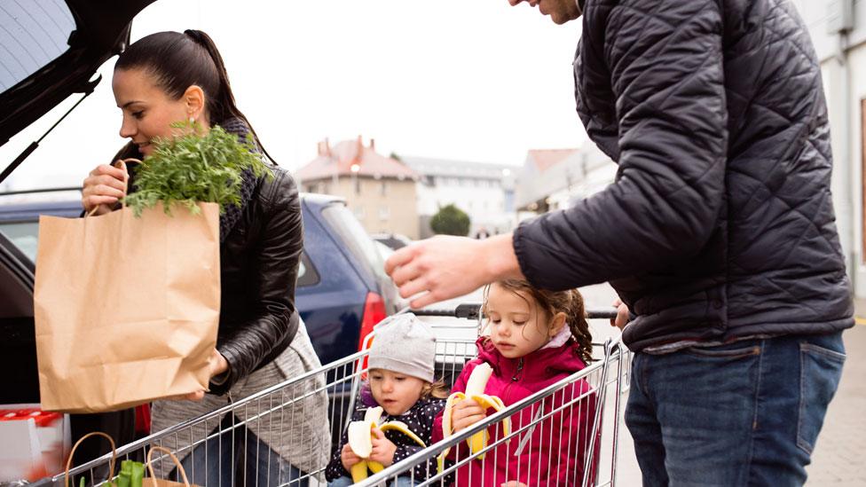 A woman loading paper bag into a car