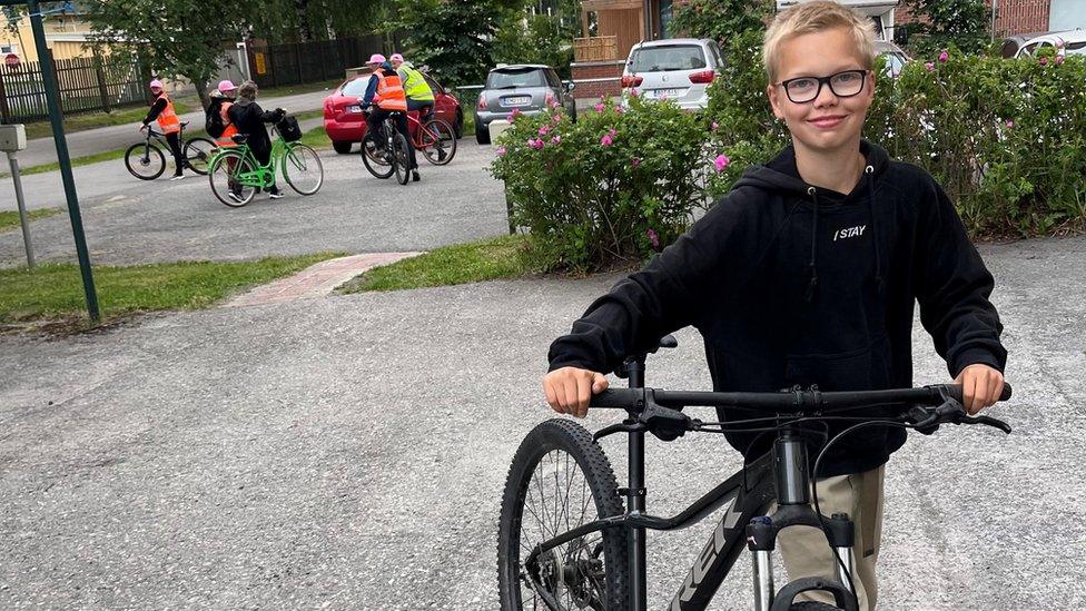 Valo stands smiling with his bike