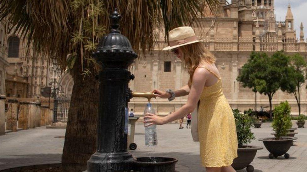 A woman fills a bottle of water during a heatwave in Seville on July 12, 2022