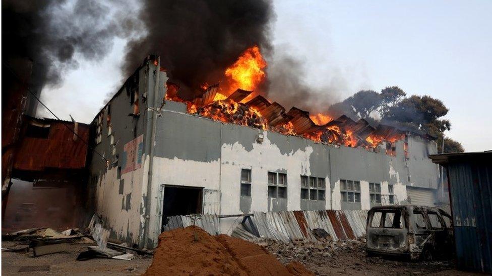 A business is set on fire during widespread looting and protests in Durban, South Africa, 12 July 2021. Former South Africa President Zuma was arrested on 07 July, and sentenced to 15 months in prison for contempt of court. Protests by his supporters included shops being looted, burned cars and the blocking of city streets in the country