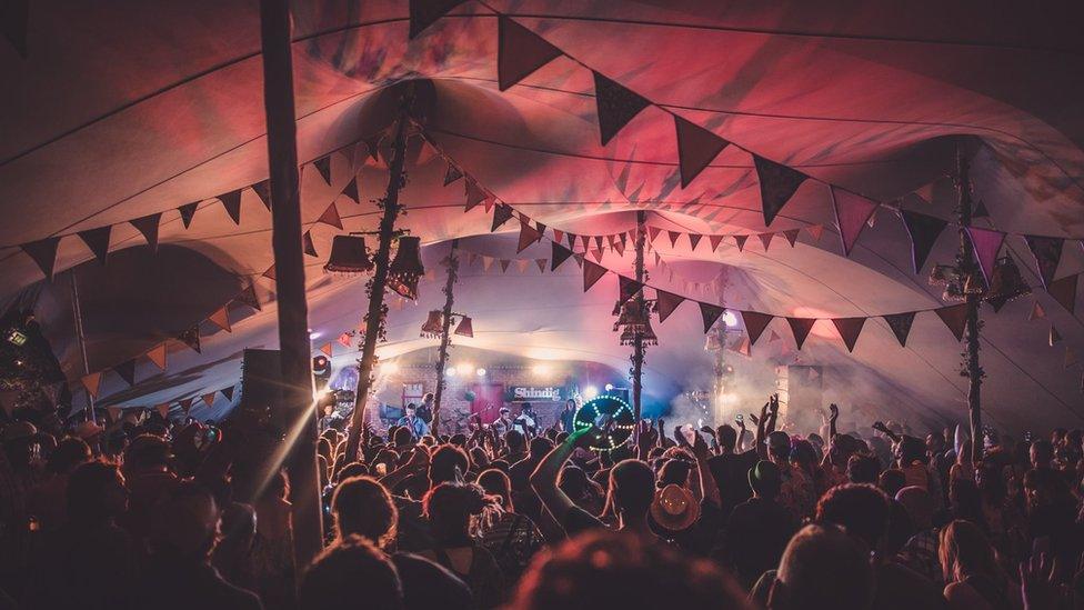 A full tent at Shindig with bunting and lampshades hanging from the ceiling