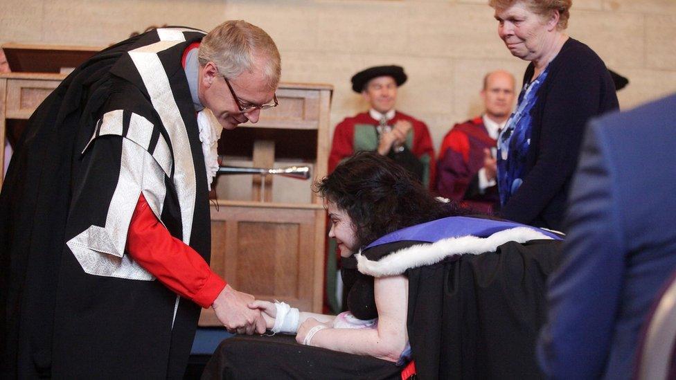 Melanie Hartshorn accepting her degree as she lies on a stretcher