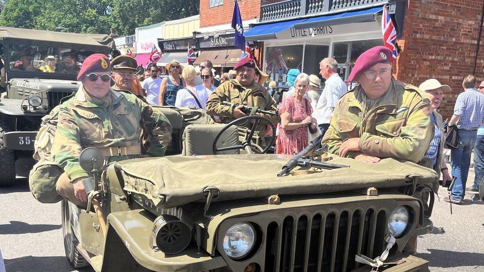 People dressed as wartime soldiers sitting on military vehicles