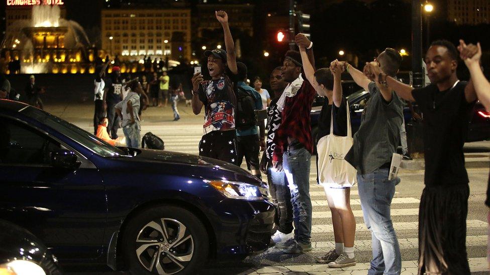 Group of protestors stand in fron of car holding hands in response to police shootings of African-Americans in USA