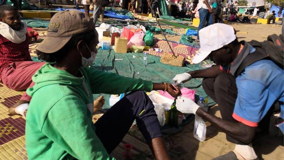 A Sudanese protester tends to the wounds of a fellow demonstrator during a rally in front of the military headquarters in the capital Khartoum on April 9, 2019.