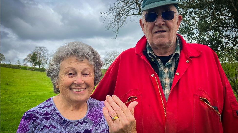 Pete and Marilyn Birch standing in a field with Marilyn holding her hand up showing the ring