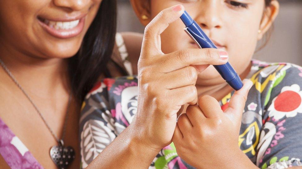 Woman helping a child to test her bloody sugar level