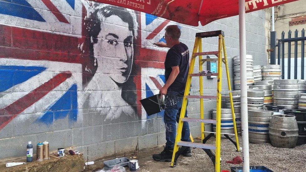 Man painting mural of the Queen