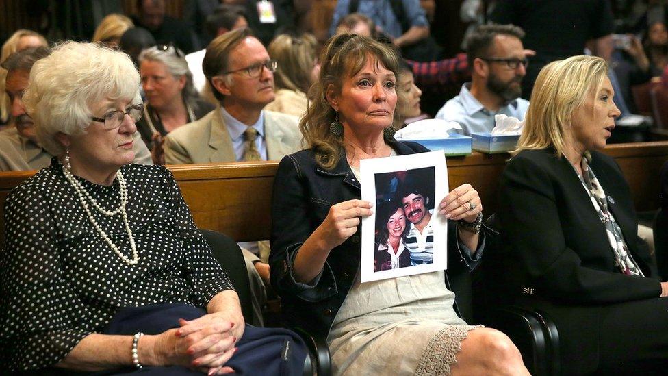 An attendee holds a photo of Cheri Domingo and her boyfriend Gregory Sanchez, who were killed in 1981.