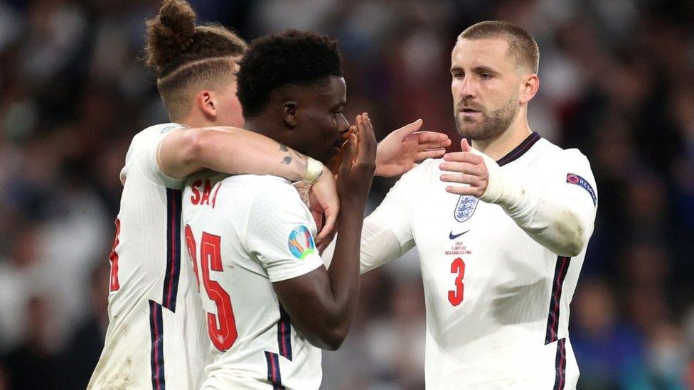 England's Bukayo Saka looks dejected after losing the penalty shootout as Luke Shaw and Kalvin Phillips console him