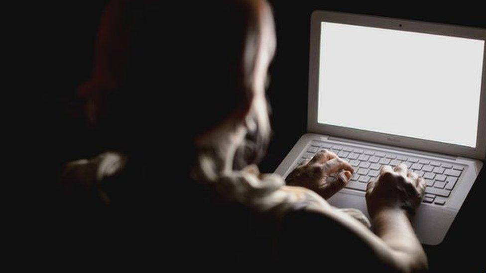 Silhouette of woman about to type on a laptop screen (nothing visible on screen)