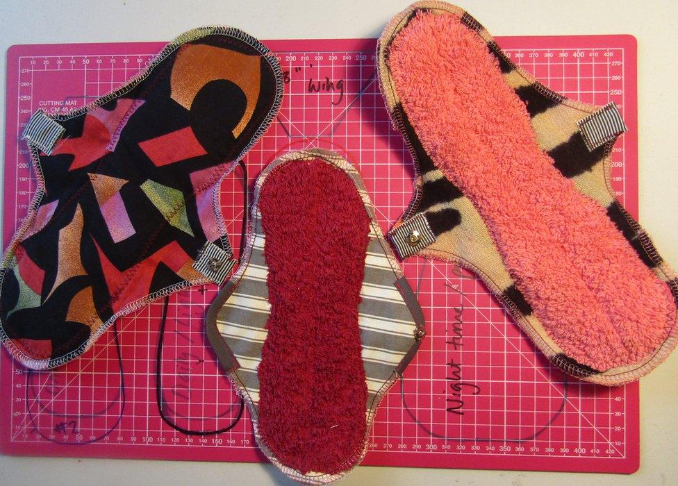 Three reusable menstrual pads laid out on a cutting mat