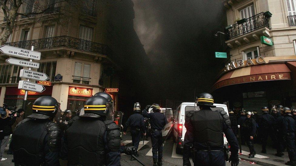 Riot police advance in a street where protesters burned cars after a march against the Youth Employment Contract on March 23, 2006 in Invalides square in Paris, France.