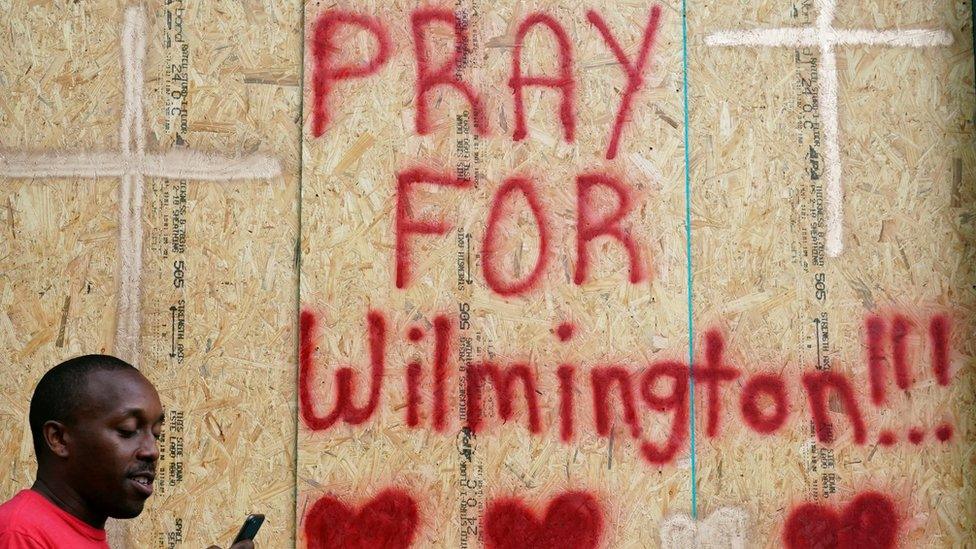 A man walks past a boarded up business before Hurricane Florence comes ashore on Wilmington, North Carolina