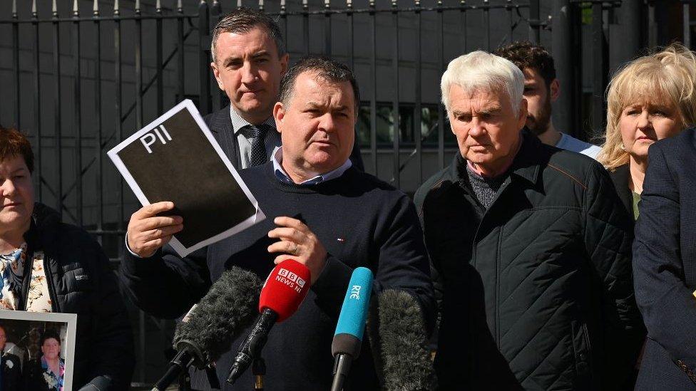 Family with redacted documents outside court