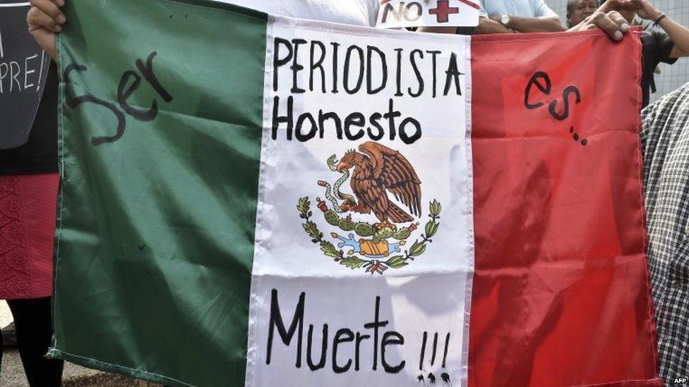 A woman holds Mexican flag with an inscription that reads "To Be a Honest Journalist is Death" during a demonstration on 1 August, 2015,