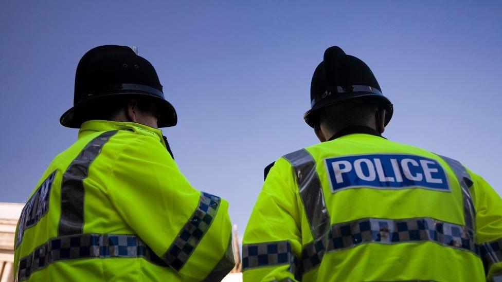 Two police officers wearing high vis jackets seen from behind