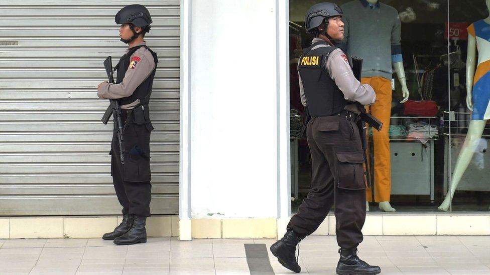 Two Indonesian anti-terror policemen stand guard next to the Starbuck cafe after several blasts and shootings in Jakarta (14 January 2016)