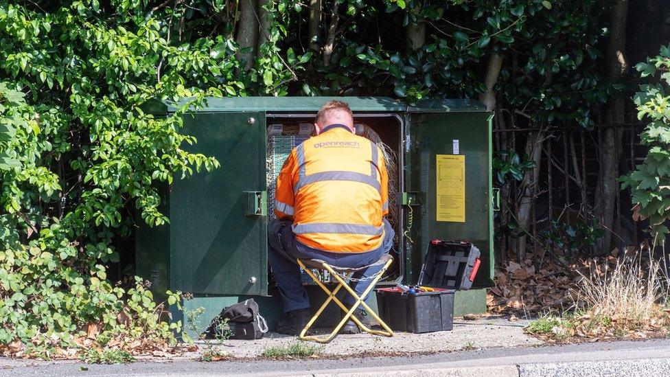 Engineer working in a green box with communications cables