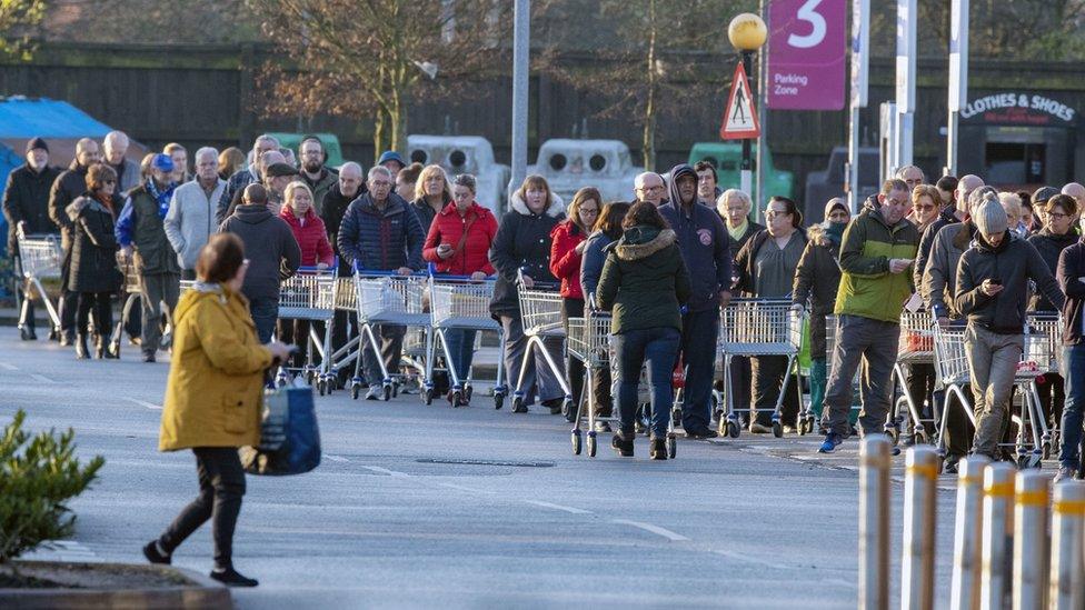 Shoppers queue outside a Tesco supermarket in Liverpool before it opens