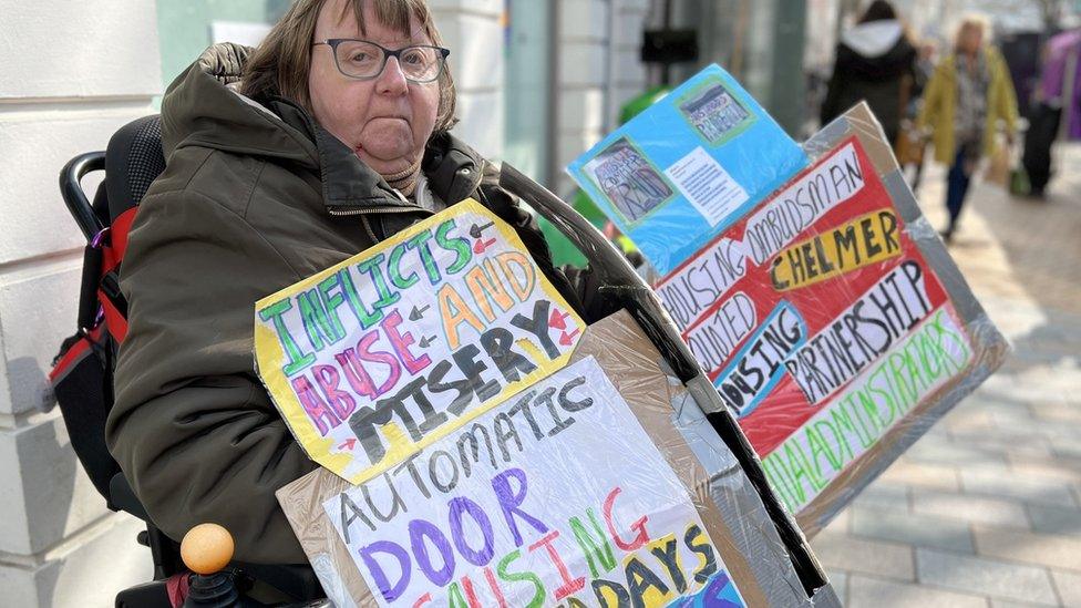 Carol Aldridge on Chelmsford High Street with protest banners