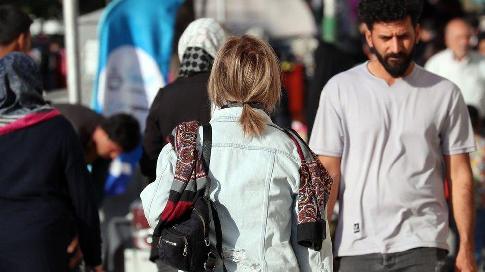 A woman without a headscarf walks down a street in Tehran, Iran (6 October 2023)