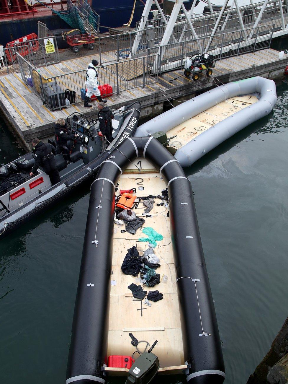 A view of boats thought to have been used in a migrant crossings as a group of people thought to be migrants are brought into Dover