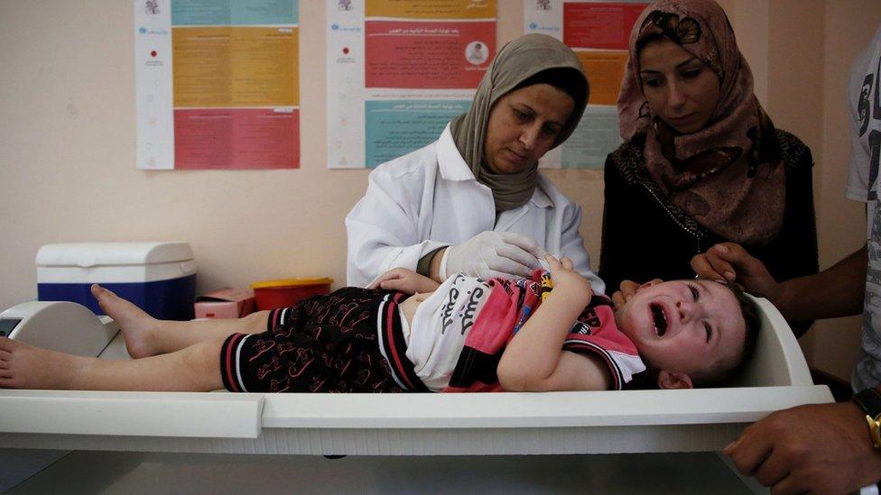 A Palestinian child receives medical check ups and aid from the Unrwa mobile team in the West Bank city of Hebron, 9 August 2018