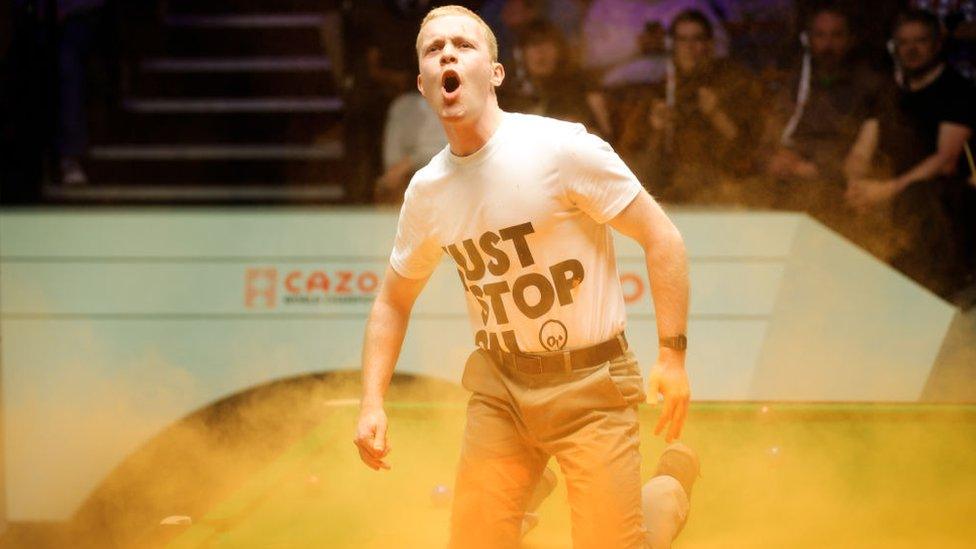 A Just Stop Oil protester jumps on the table and throws orange powder