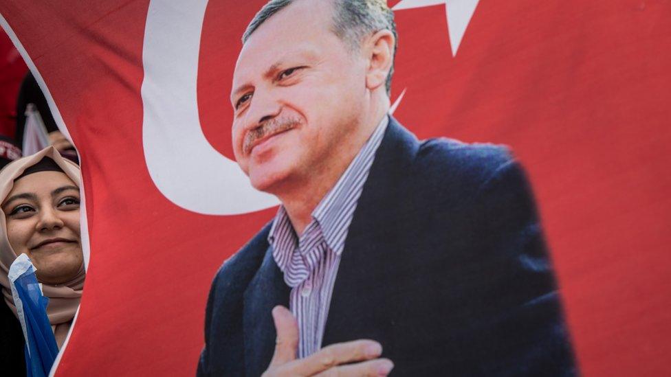 A woman holds a flag of Turkey's President Recep Tayyip Erdogan during a AK Parti election rally