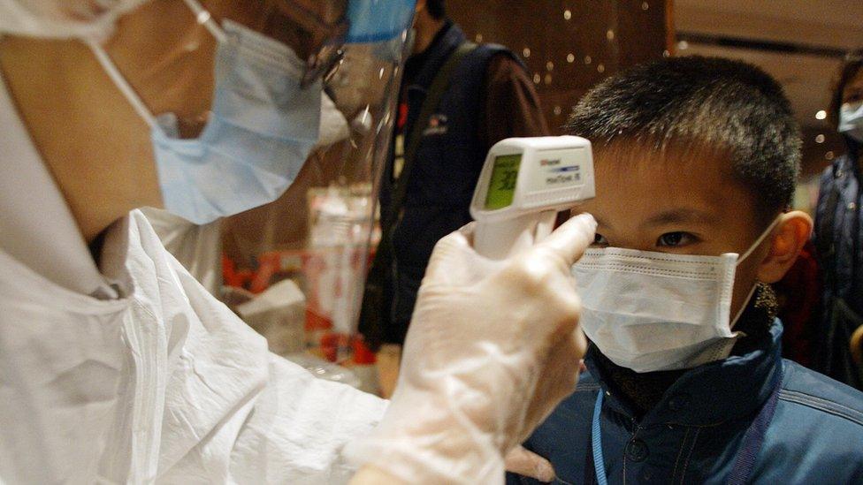 A boy has his temperature taken as he arrives at the Queen Elizabeth hospital in Hong Kong, 20 January 2004