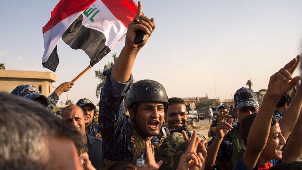 Iraq's federal police wave the national flag as they celebrate in the Old City of Mosul, 9 July 2017