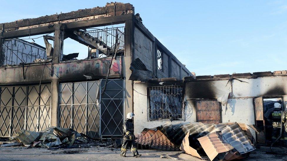 Firefighters douse the remaining fire in burnt houses and property in the village of Blas-Batyr