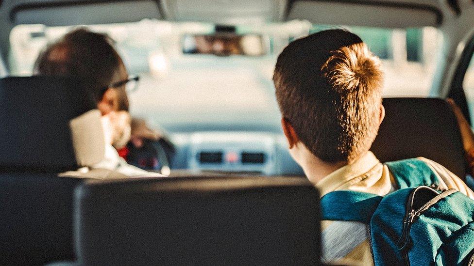 Stock image of an adult driving a child to school