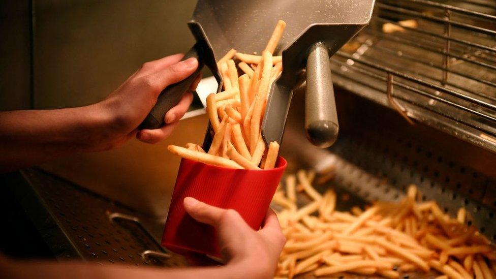 An employee serves french fries in a reusable container at a McDonald's restaurant in Levallois-Perret, near Paris