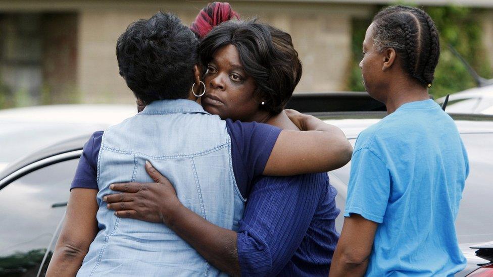 Pastor Mary Moore, left, meets with neighbours outside the home