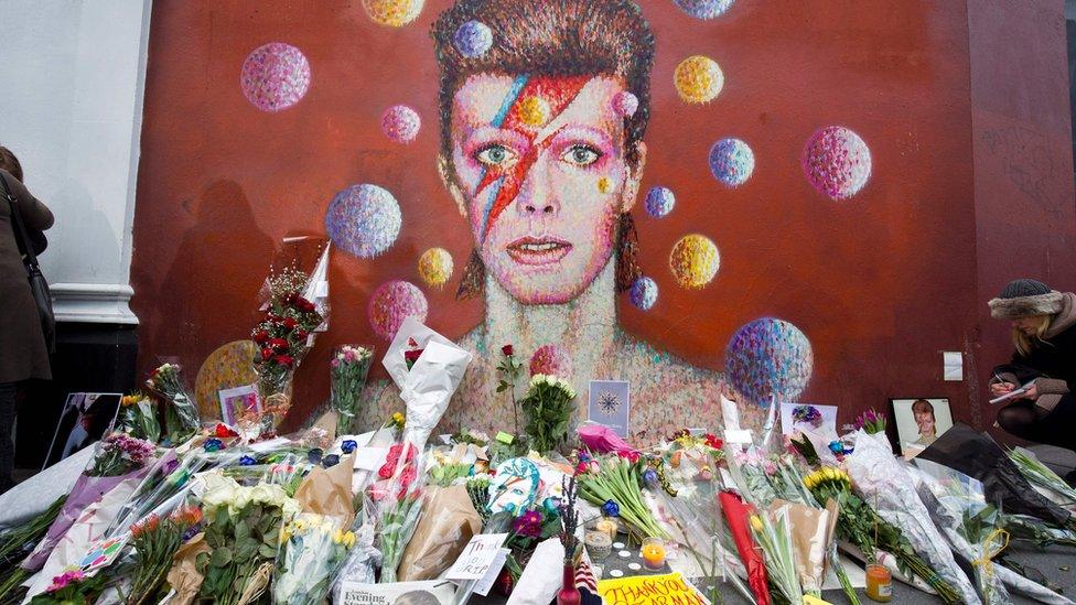 Flowers start to mount up by David Bowie mural in Brixton