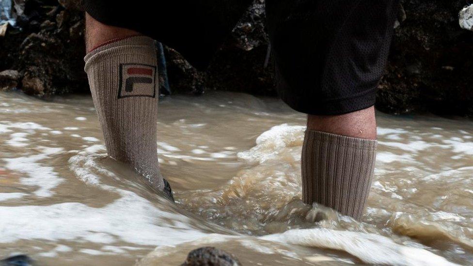 A man searches for scrap metal in the polluted waters of the Las Vacas river