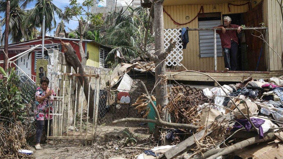 Two residents of San Isidro, Puerto Rico stood outside their damaged house after Hurricane Maria struck the island.