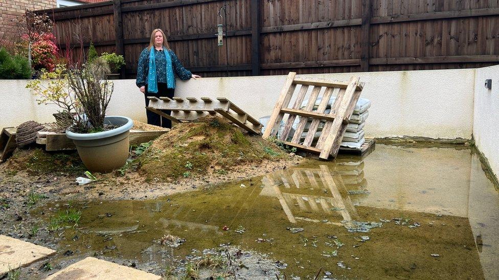 Karen Fisher standing in her garden which resembles a pond