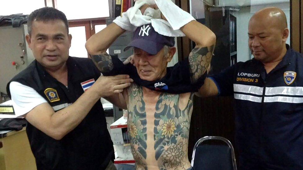 Thai policemen with Mr Shirai, displaying the tattoos on his body