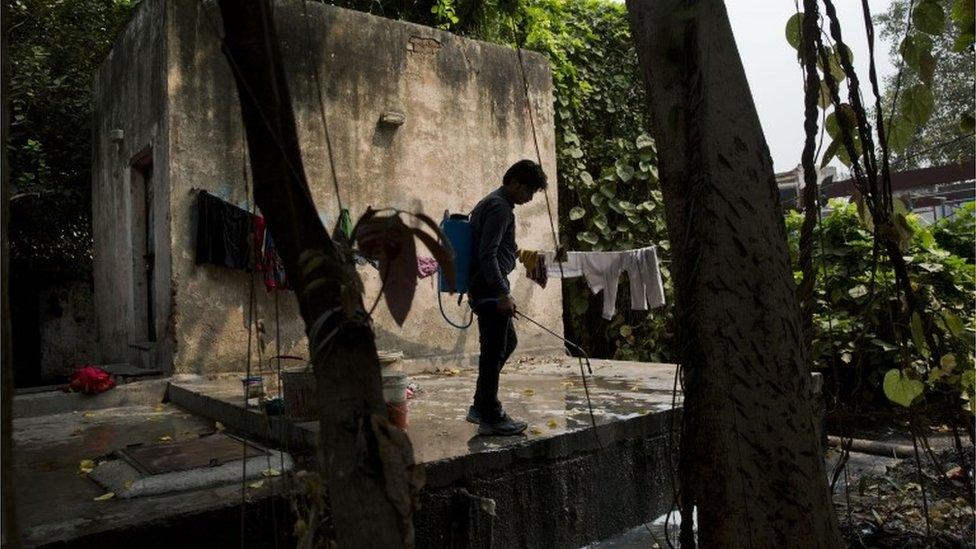 A municipal worker sprays disinfectants on sewage water near a hospital to prevent mosquitoes from breeding in New Delhi, India, Wednesday, Sept. 16, 2015.